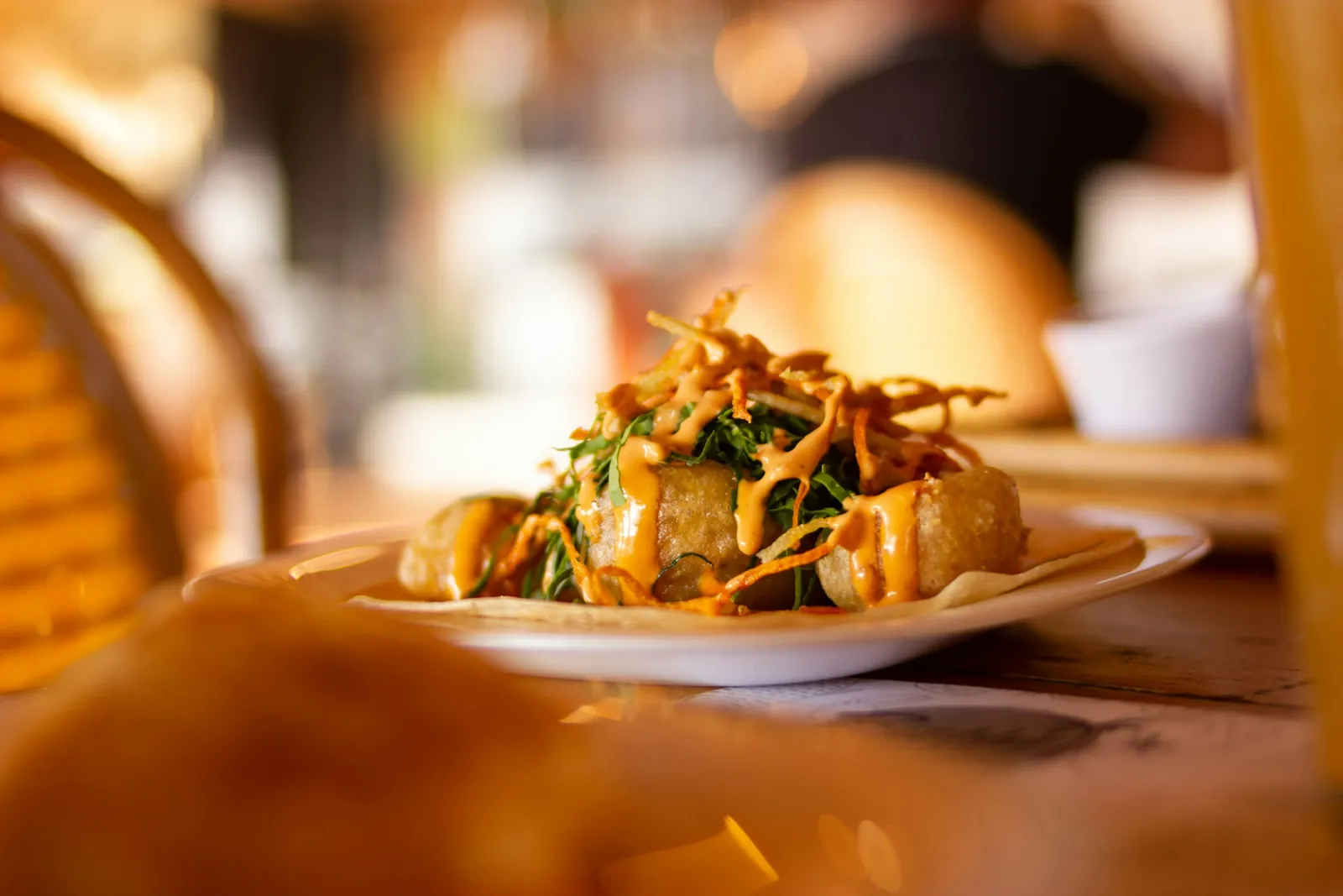 A plate of food with crispy toppings in warm restaurant light