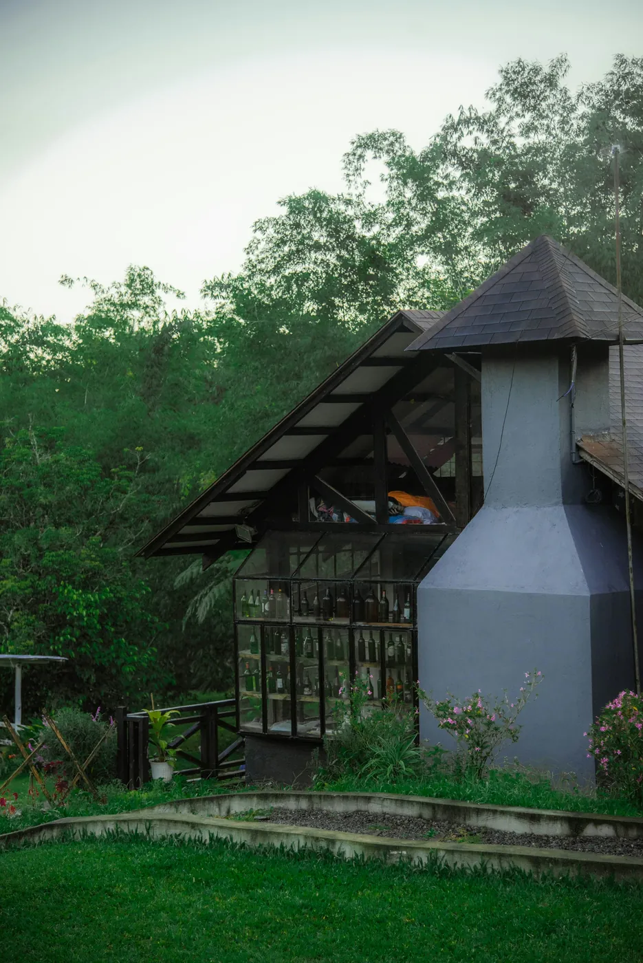 A wood and glass cottage surrounded by tropical garden