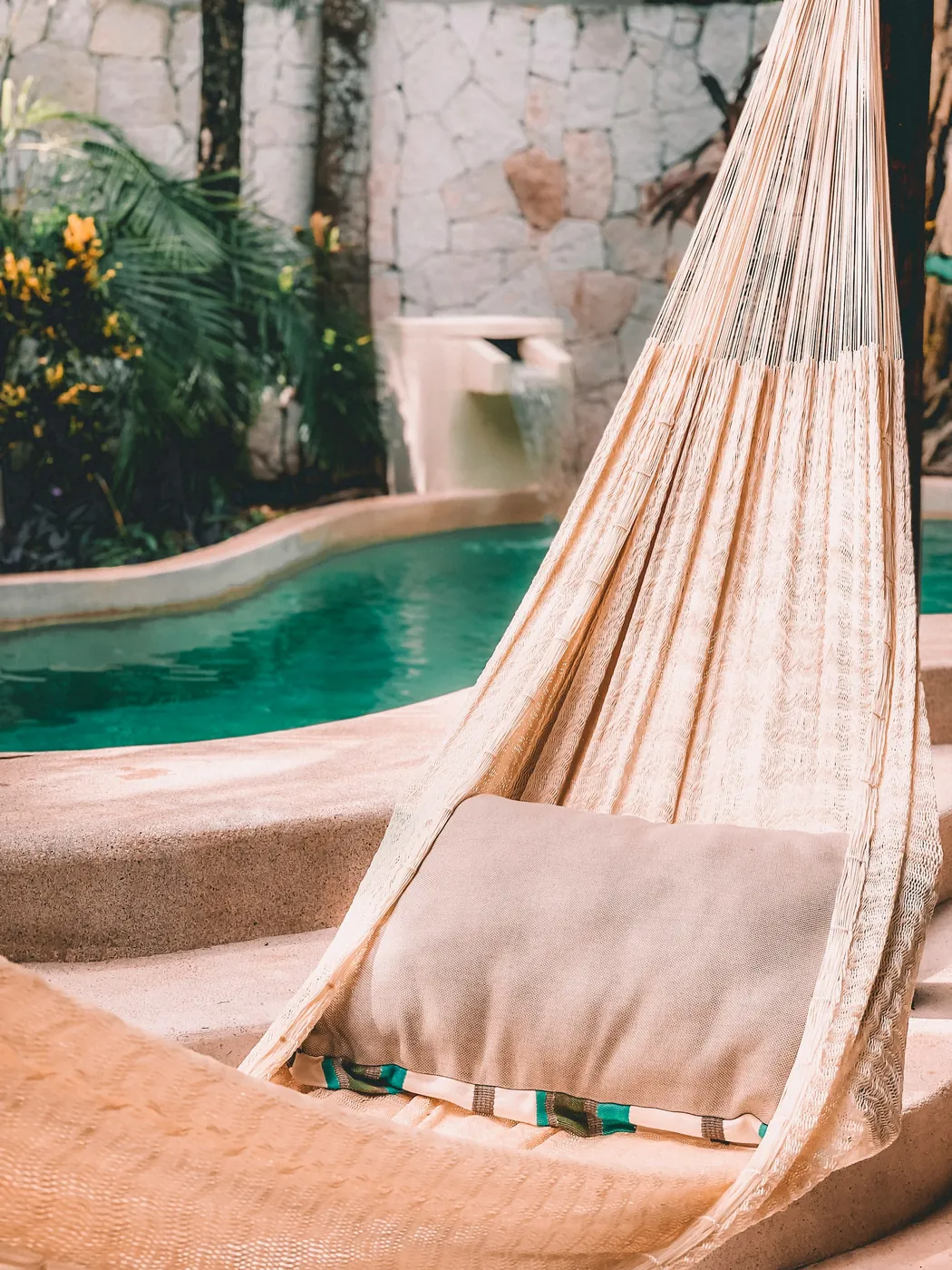 A woven hammock beside a small turquoise plunge pool