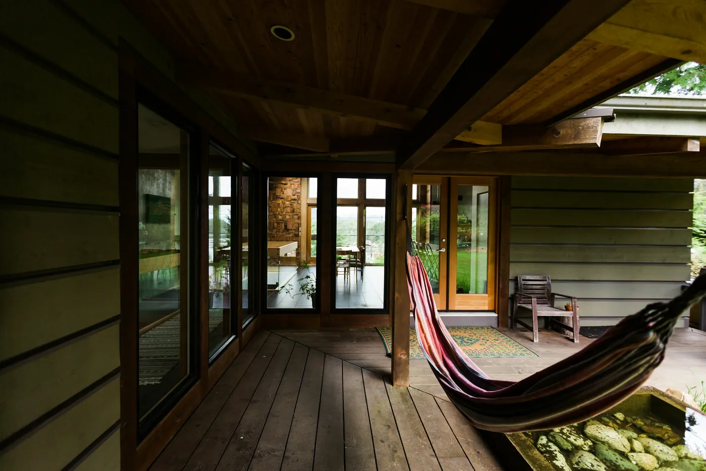 A wooden porch with a striped hammock looking out to trees